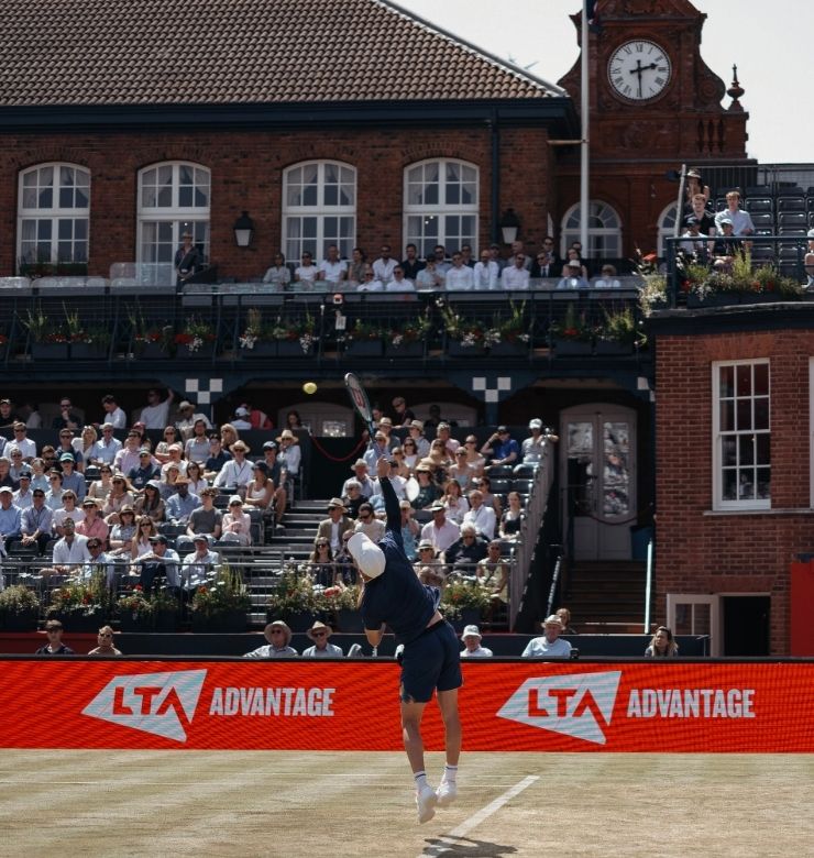 Tennis player taking a serve with spectators in the background