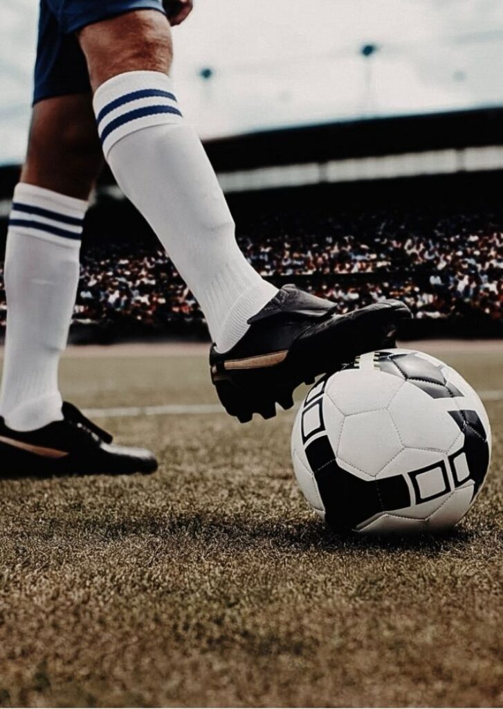 football held by someone standing with football boots