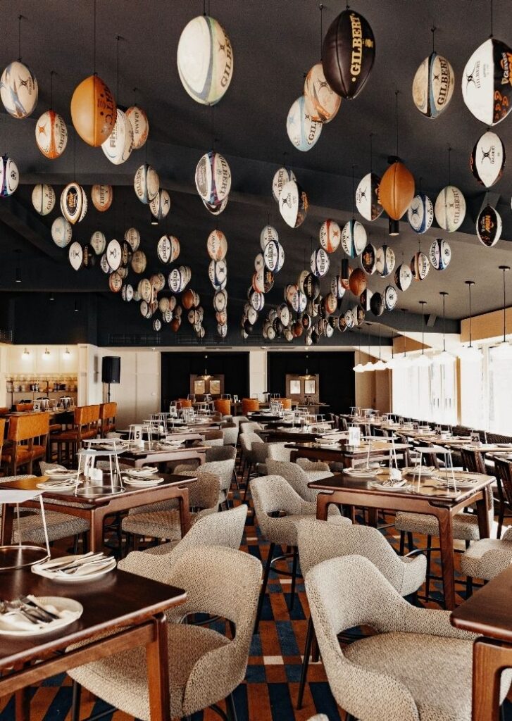 Inside of rugby hospitality venue with tables and chairs and rugby balls